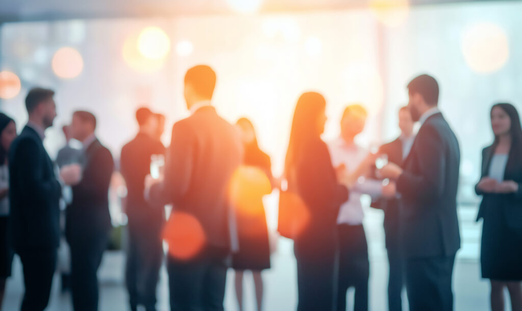 A vibrant networking event with business professionals engaging in conversation, blurred figures creating a sense of motion and activity -