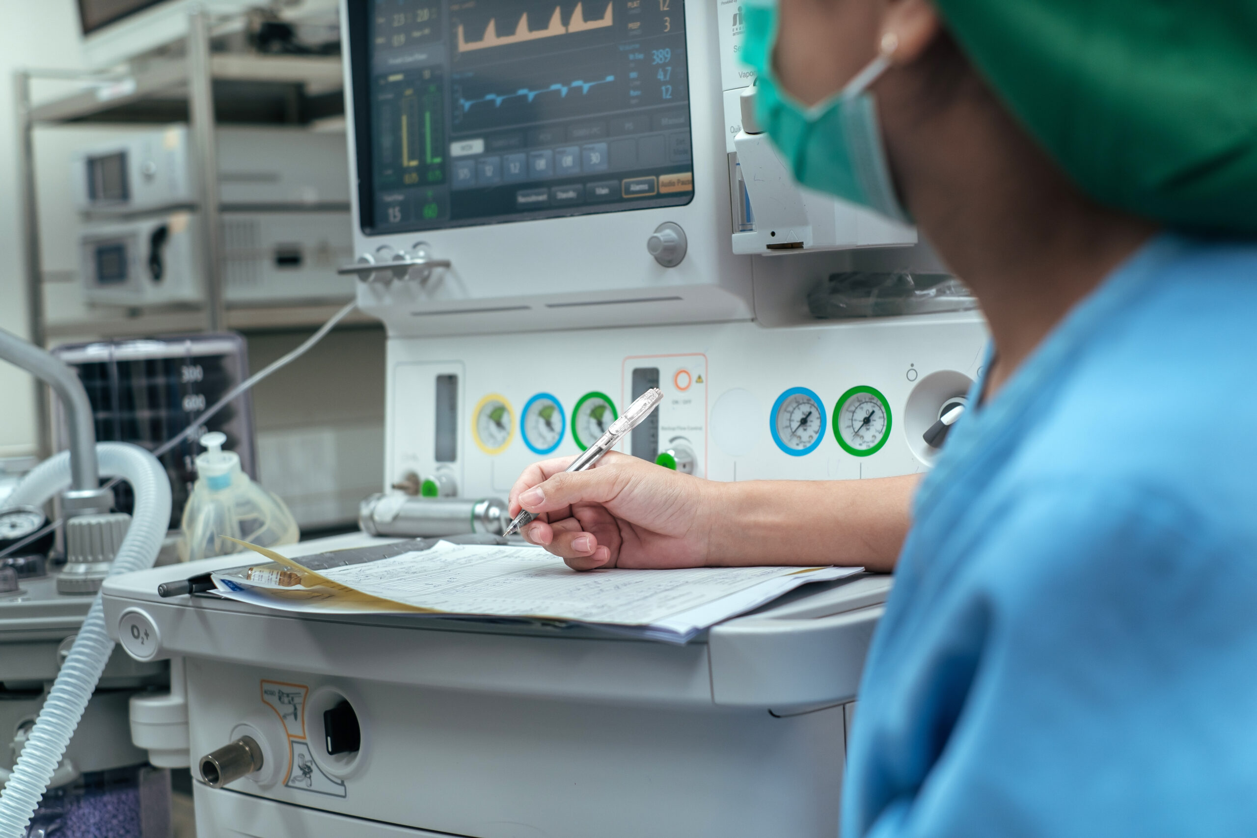 Selective focus hand Anesthetist working control anesthetic and unconscious with computer monitor in surgery procedure at operating room. -